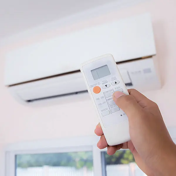 person using a remote control for an air conditioning system