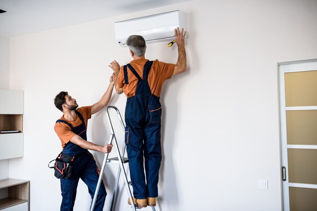 Two workers installing an air conditioner